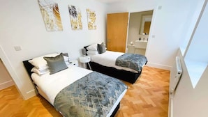 A bedroom with two beds, a small bedside table, and a mirror.