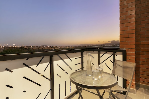 Enjoy the city view from this balcony with a table, chair, and glass top.