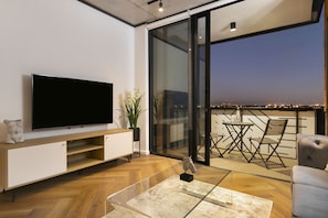 Relax in this stylish living room with a flat-screen TV, glass coffee table, and comfortable sofa.