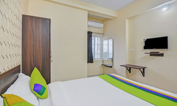 A hotel room with a bed, a TV mounted on the wall, a window with curtains, and a door. - Treebo Everest Residency Tidel Park (Coimbatore)