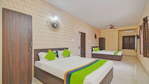 A hotel room with two beds, a wooden wardrobe, a decorative wall piece, and a ceiling fan. - Treebo Everest Residency Tidel Park (Coimbatore)