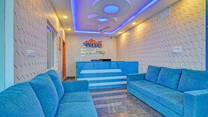 A reception area with a blue sofa, a reception desk, and a ceiling fan. - Treebo Everest Residency Tidel Park (Coimbatore)