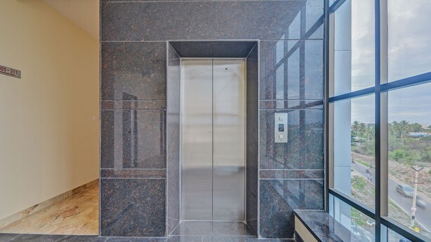 An elevator in a building with a modern design, featuring a control panel with buttons and a small display. - Treebo Everest Residency Tidel Park (Coimbatore)