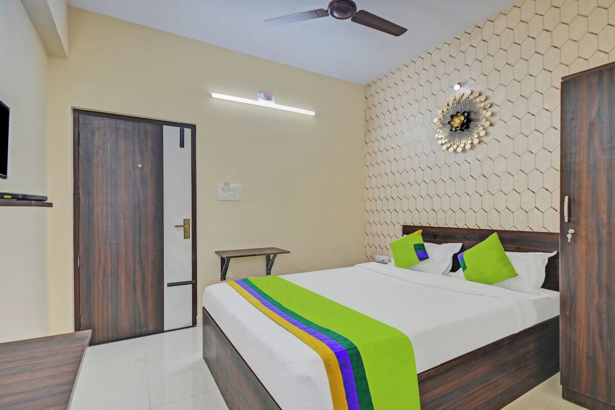 A bedroom with a bed, a ceiling fan, a wall-mounted light, and a door.
