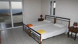 A bedroom with a bed, two nightstands, a window, and a balcony with a view. - Paterakis Studio's Triopetra (Agios Vasileios)
