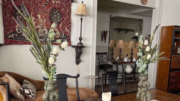 A dining area with a wooden table, two decorative vases with flowers, a candle, and a red tapestry on the wall. - Beautiful, artistic, unique and beyond large and spacious apartment (Little Falls)