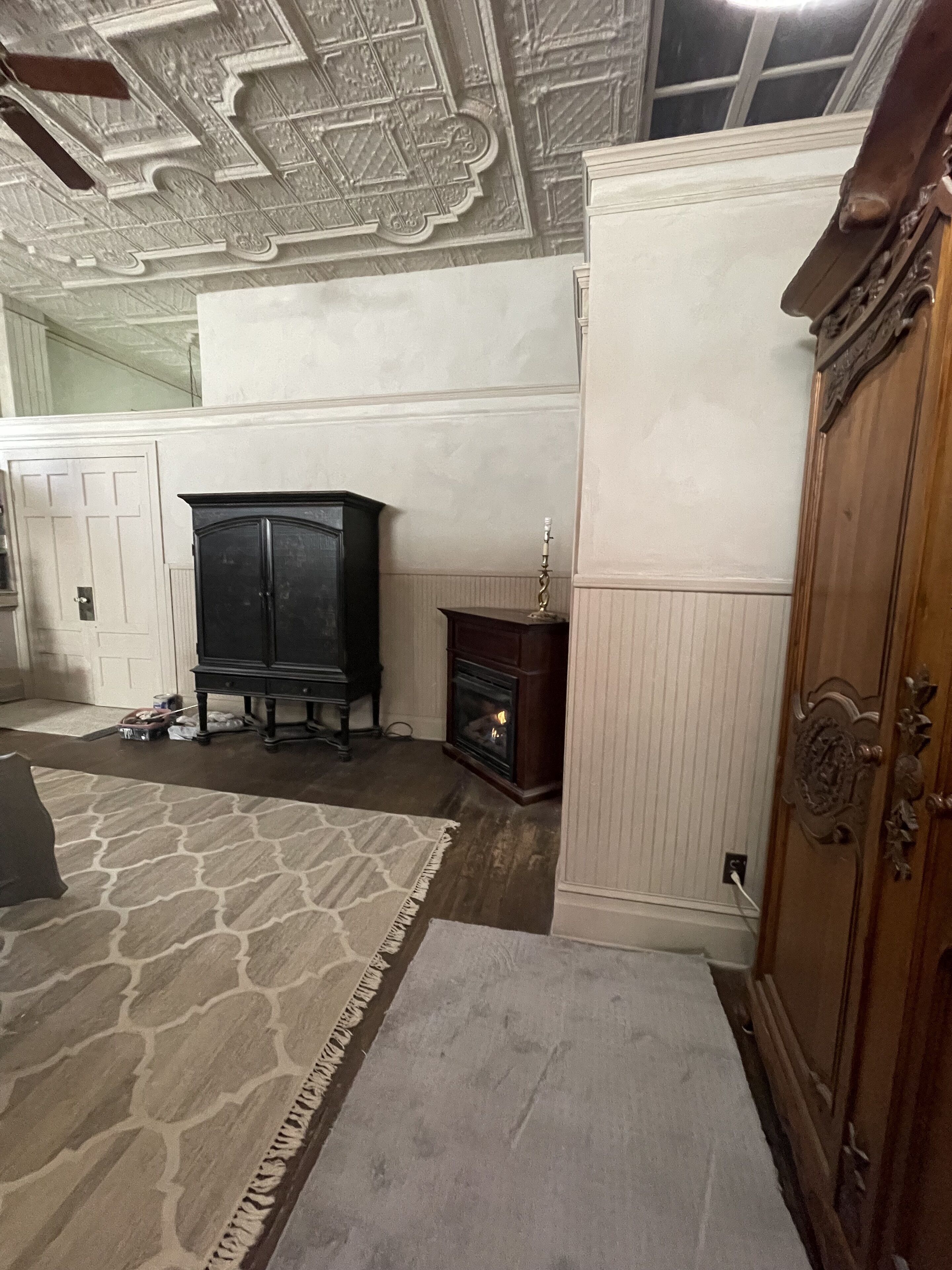 A room with a fireplace, a wooden cabinet, and a patterned rug.