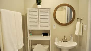 Une salle de bain comprenant des toilettes, un lavabo et un meuble avec un miroir au-dessus.