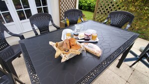 Ein Tisch ist gedeckt mit Brot, Butter, Marmelade und Getränken, umringt von schwarzen Stühlen.