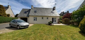 A two-story house with a sloped roof, a garage, and a well-maintained lawn.