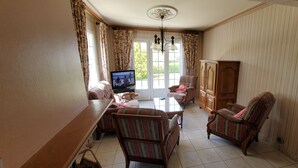 Ein Wohnzimmer mit Fernseher, Sofa, Sessel und Holzschrank.