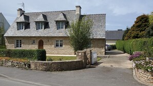 Ein Haus aus Stein mit einem geneigten Dach, zahlreichen Fenstern und einem ehrfurchtgebietenden Einfahrtstor.