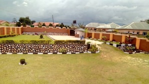 A residential area with houses, a stone wall, and a well-maintained lawn. - A & J Holiday Suites - Fort Portal (Bouvet Island)