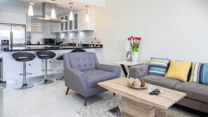 Una cocina moderna con una isla central, taburetes de bar e iluminación colgante.