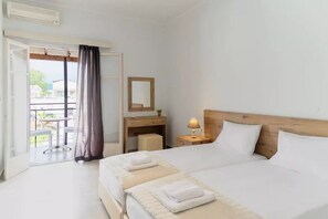 Relax in this serene hotel room with a large bed, desk, and balcony offering a view of the outside.