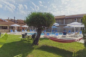 Relax by the pool surrounded by lush greenery and comfortable seating.