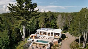 Une maison moderne avec une piscine, entourée d’une forêt.