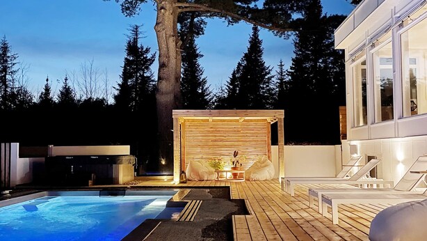 Un espace piscine extérieur moderne, doté d’une terrasse en bois, d’un jacuzzi et d’un grand arbre.