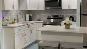 A modern kitchen with white cabinets, stainless steel appliances, and a central island with stools.