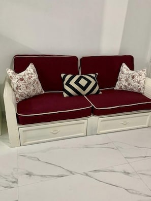 A red sofa with floral cushions and a geometric-patterned pillow.
