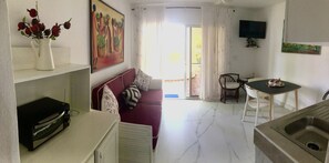 A compact living space with a kitchenette, a dining area, and a sofa.