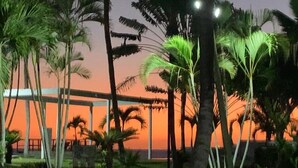 A nighttime view of a resort with palm trees and a sunset in the background. - ON THE Caribbean SEA - Crystal Apartment (Boca Chica)