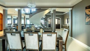 A dining area with a spiral staircase, modern chairs, and a chandelier.