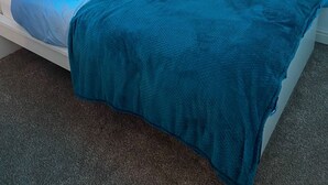 Une chambre à coucher avec un lit, un néon, une fenêtre et un radiateur.