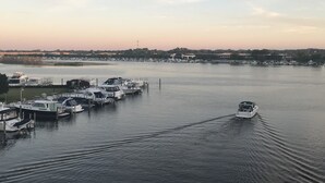 Un puerto deportivo con barcos amarrados, cielo despejado y una costa lejana con edificios.