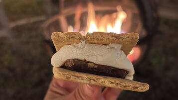 Eine Hand hält einen S'more mit Marshmallows und Schokolade zwischen Graham Crackern.