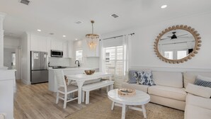 Une cuisine moderne avec des meubles blancs, un réfrigérateur en acier inoxydable et un lustre.