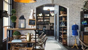 L’intérieur d’un restaurant avec des murs en briques, des meubles en osier, un panneau noir et un mannequin portant une chemise bleue.