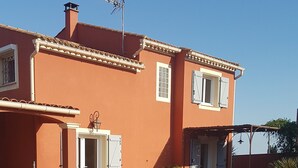 Ein Haus mit Swimmingpool, überdachter Terrasse und blauem Himmel.