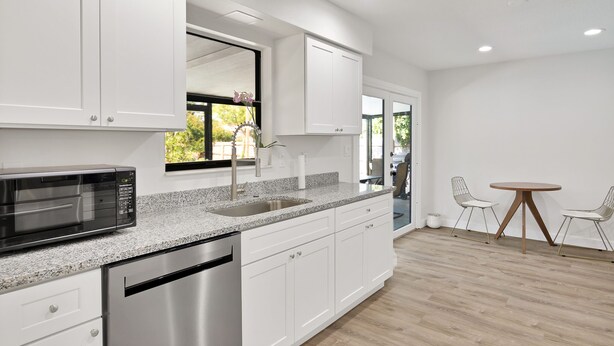 A modern kitchen with white cabinets, a stainless steel dishwasher, a built-in microwave, and a granite countertop. - Relax and Unwind in 2 BR apt with Private Heated Pool (Sebastian)