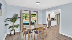 A modern room with a dining table, chairs, a potted plant, and a view of a swimming pool. - Relax and Unwind in 2 BR apt with Private Heated Pool (Sebastian)