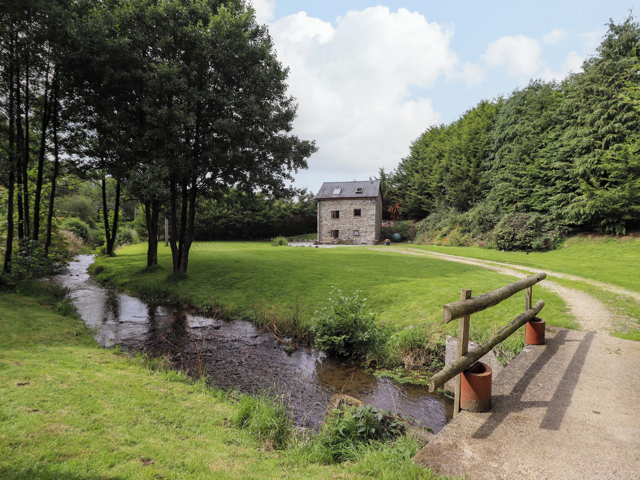 A stone building with a grassy field and a small stream.