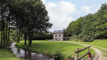 A stone building with a grassy field and a small stream.