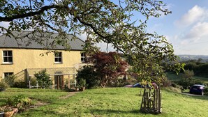 A house with a glass conservatory, a lawn, and a tree. - Frizenham Farmhouse B&B (Torrington)