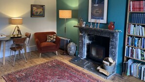 A cozy living room with a fireplace, a bookshelf, and a patterned rug. - Frizenham Farmhouse B&B (Torrington)