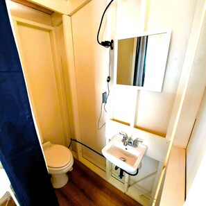 A small bathroom with a toilet, a sink, and a mirror. - Lakefront Glamping in a Tiny A-Frame Cabin with a Fabulous View, near Acadia (Mariaville)