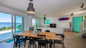 A modern kitchen with a dining area, large windows, and a view of the sea. - Villa with exceptional views (Labin)