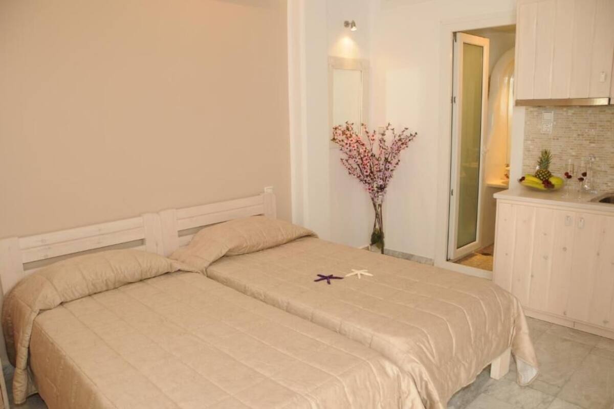 A bedroom with a bed, a nightstand, a mirror, and a vase with flowers.