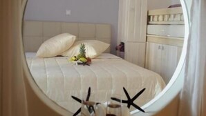 Un dormitorio con cama, almohadas, una mesita de noche y un espejo que refleja la habitación.