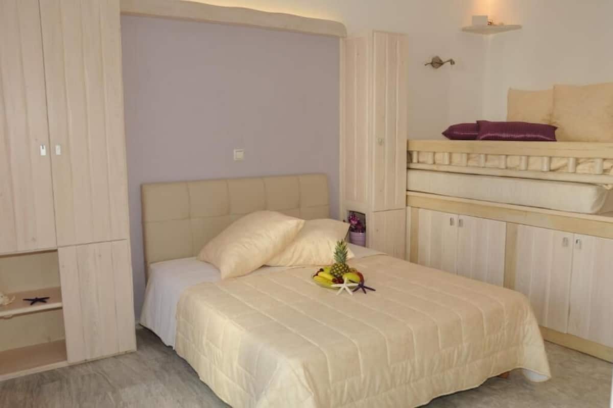 A bedroom with a bed, a small table with fruit, and built-in wardrobes.