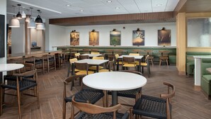 A restaurant with round tables and chairs, a green booth seating area, and artwork on the walls. - Fairfield Inn & Suites by Marriott Boise West (Boise)