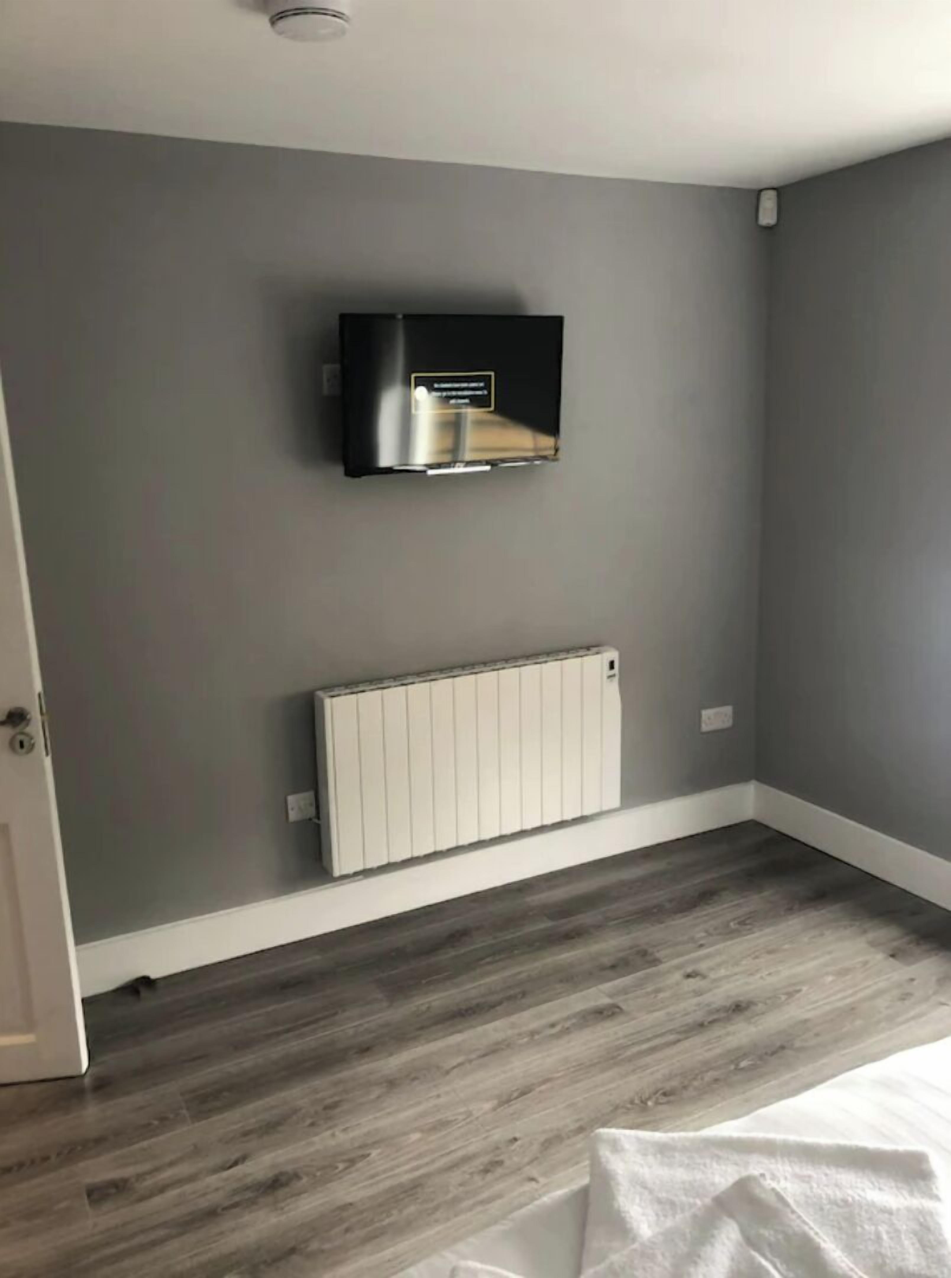A room with grey walls, a white radiator, and a mounted TV.