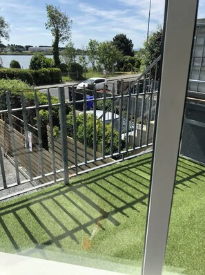 Een uitzicht op een omheind buitengebied met een gazon, een metalen hek en een gebouw op de achtergrond.
