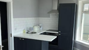 A modern kitchen with dark cabinets, a white countertop, and a built-in stove.