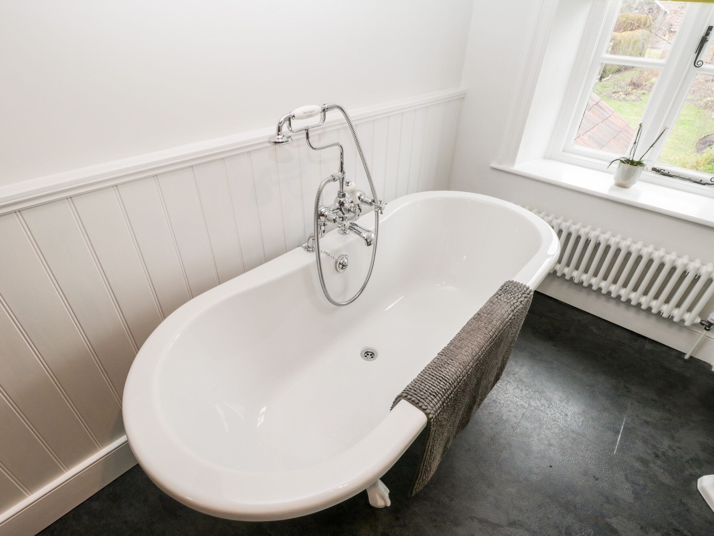 Ein Badezimmer mit freistehender Badewanne, einem Fenster mit Ausblick und einer Heizung.