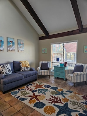 Una sala de estar con un sofá azul, sillones a rayas, un tapete estampado y obras de arte en las paredes.